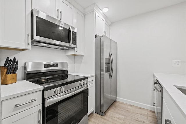 kitchen with light wood-type flooring, white cabinetry, baseboards, and stainless steel appliances