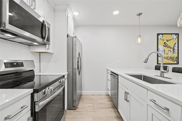 kitchen featuring a sink, light wood finished floors, stainless steel appliances, recessed lighting, and white cabinetry