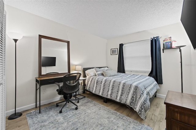 bedroom with baseboards, a textured ceiling, and wood finished floors