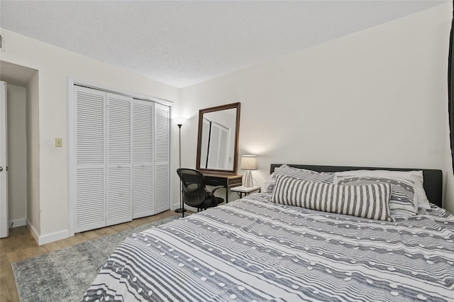 bedroom featuring a textured ceiling, baseboards, wood finished floors, and a closet