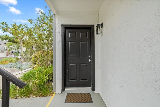 doorway to property featuring stucco siding