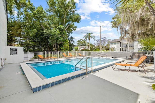 community pool with a patio and fence