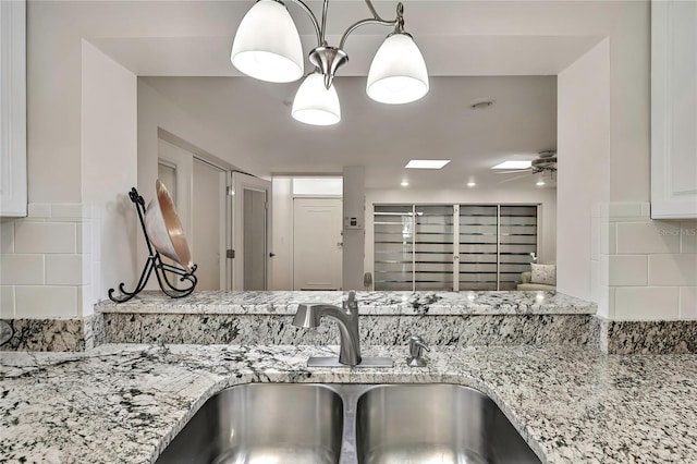 4175 Northmeadow Cir Unit 4175, Tampa, FL 33618 - kitchen view of a sink, backsplash, light stone countertops, white cabinetry, and a ceiling fan