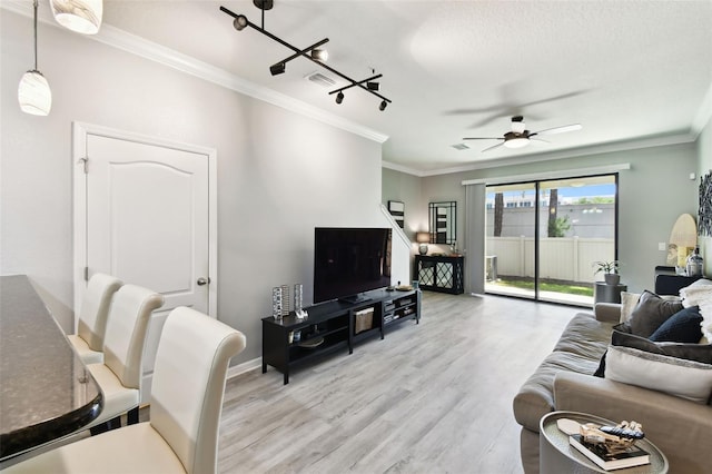 living room featuring visible vents, ornamental molding, light wood-style floors, baseboards, and a ceiling fan