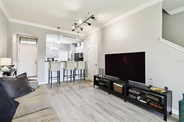 living area with crown molding, arched walkways, baseboards, a chandelier, and light wood-style flooring