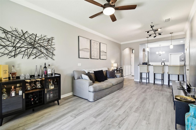 living area featuring ceiling fan, arched walkways, wood finished floors, visible vents, and a bar
