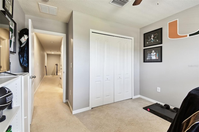 interior space featuring visible vents, baseboards, ceiling fan, and light colored carpet