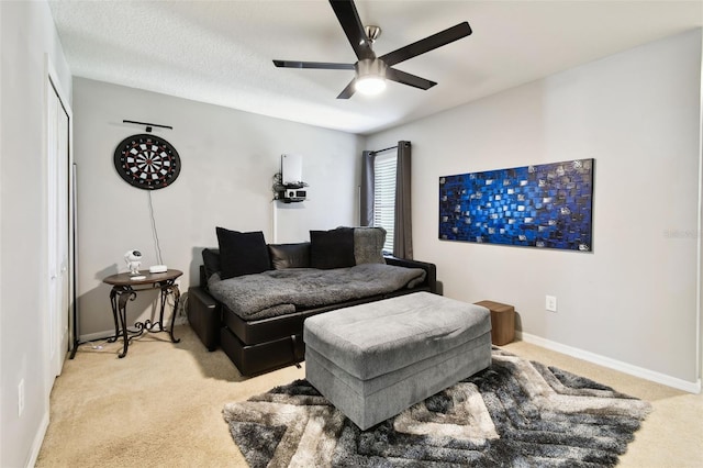living room featuring baseboards, ceiling fan, and light carpet