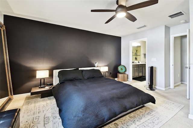 bedroom with baseboards, visible vents, light carpet, and ensuite bath