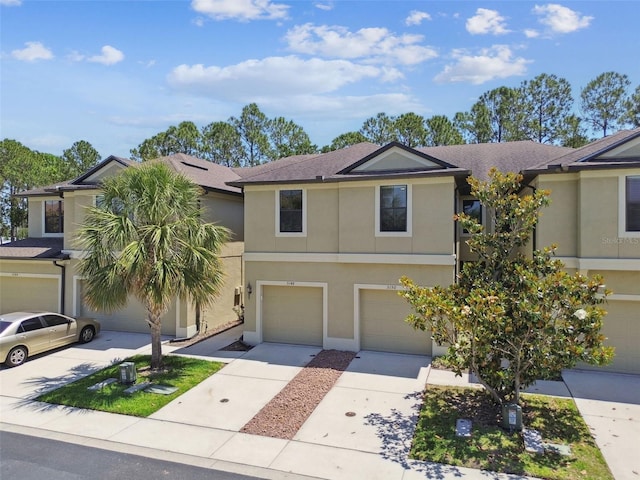 view of property featuring an attached garage, driveway, a shingled roof, and stucco siding