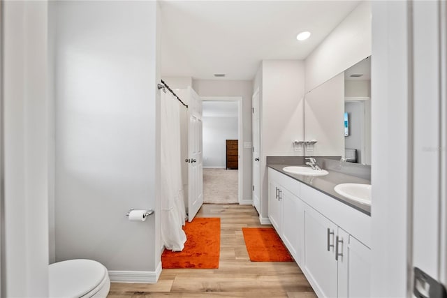 7797 Peace Lily Ave, Wesley Chapel, FL 33545 - bathroom featuring wood finished floors, toilet, baseboards, and a sink