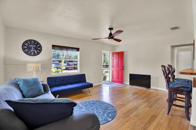living area featuring hardwood / wood-style flooring, baseboards, a ceiling fan, and visible vents