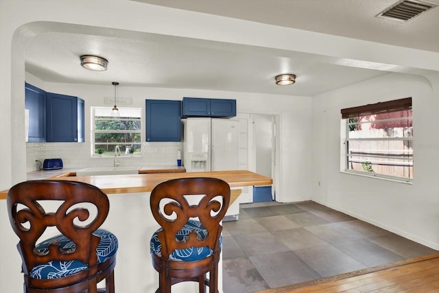 kitchen with a sink, a breakfast bar, visible vents, decorative backsplash, and blue cabinetry