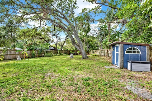 view of yard with an outbuilding, a fenced backyard, and a storage unit