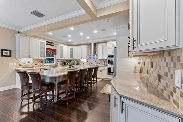 2701 W Bay Ave, Tampa, FL 33611 - kitchen with a breakfast bar area, a kitchen island, visible vents, tasteful backsplash, and wall chimney exhaust hood
