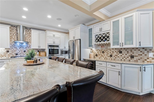 2701 W Bay Ave, Tampa, FL 33611 - kitchen featuring crown molding, a breakfast bar area, wall chimney exhaust hood, light stone counters, and appliances with stainless steel finishes