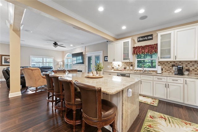 2701 W Bay Ave, Tampa, FL 33611 - kitchen with a kitchen bar, white cabinetry, light stone counters, a sink, and backsplash
