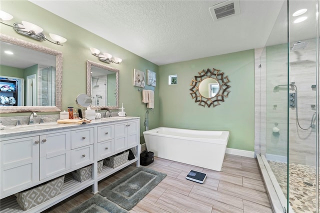 2701 W Bay Ave, Tampa, FL 33611 - full bathroom with double vanity, a textured ceiling, visible vents, a shower stall, and a soaking tub