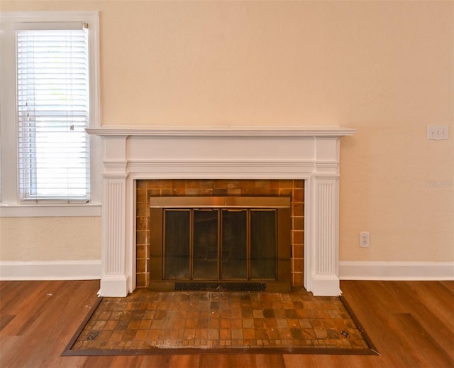 details featuring baseboards, wood finished floors, and a tile fireplace