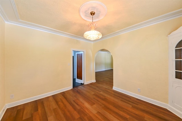 spare room featuring arched walkways, a chandelier, baseboards, wood finished floors, and ornamental molding