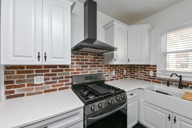 kitchen with a sink, white cabinets, wall chimney exhaust hood, and stainless steel gas stove