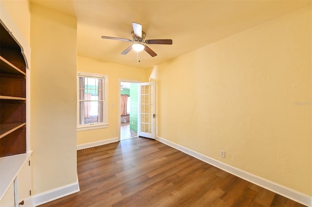 empty room featuring baseboards, a ceiling fan, and dark wood-style floors