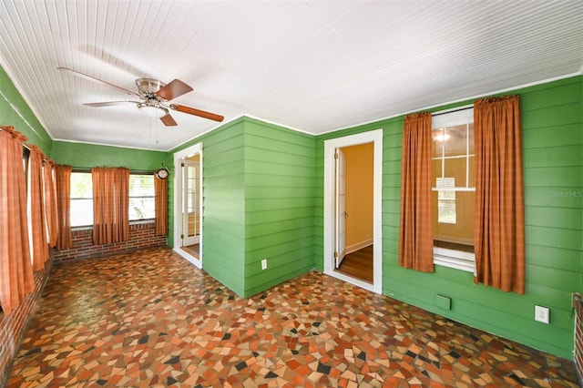 spare room featuring a ceiling fan and wooden walls