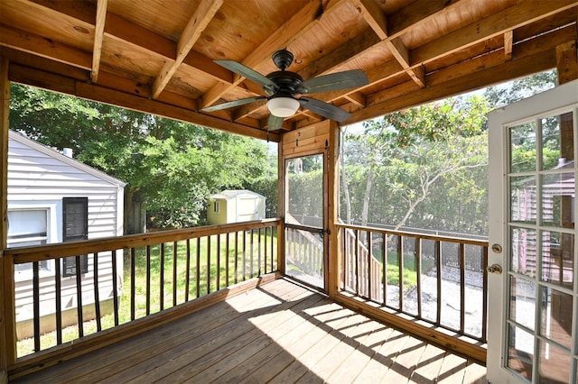 wooden deck with a storage shed, a ceiling fan, and an outbuilding
