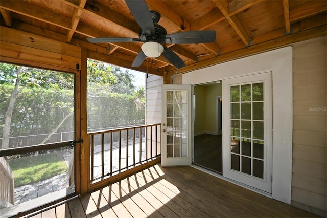 unfurnished sunroom with a ceiling fan and beam ceiling