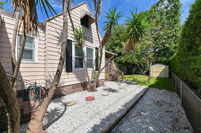 view of property exterior featuring crawl space, a lawn, fence, an outdoor structure, and a shed
