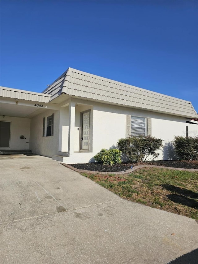 4043 La Pasida Ln, New Port Richey, FL 34655 - view of home's exterior featuring stucco siding, a carport, driveway, and mansard roof