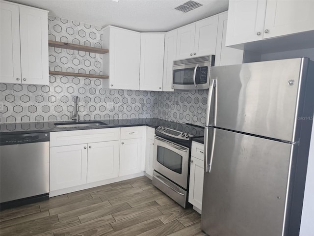 4043 La Pasida Ln, New Port Richey, FL 34655 - kitchen with open shelves, appliances with stainless steel finishes, dark countertops, a sink, and visible vents