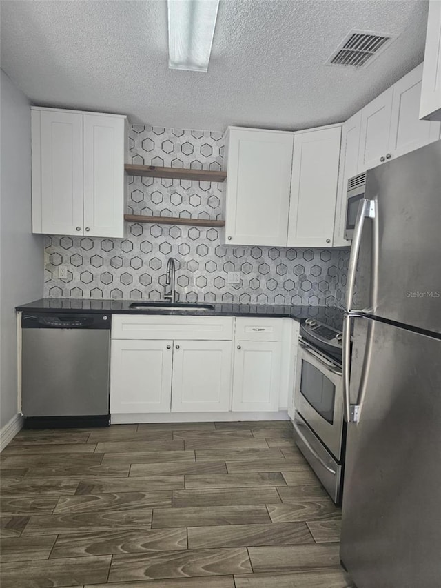 4043 La Pasida Ln, New Port Richey, FL 34655 - kitchen featuring dark countertops, a sink, stainless steel appliances, visible vents, and wood finish floors