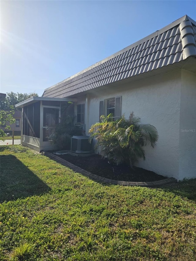 4043 La Pasida Ln, New Port Richey, FL 34655 - rear view of house with a sunroom, a lawn, stucco siding, and central AC unit
