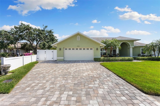 view of front of home with a garage, a front yard, decorative driveway, stucco siding, and a gate