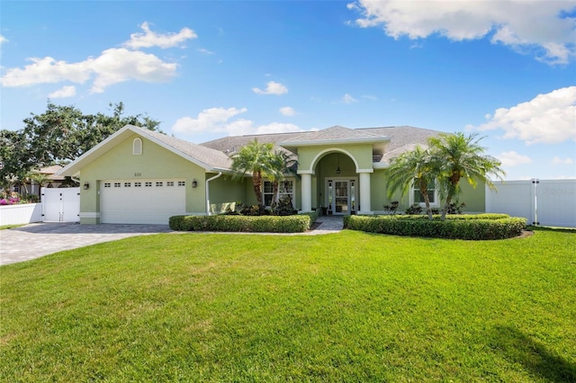 view of front of house with stucco siding, driveway, a front lawn, and a garage