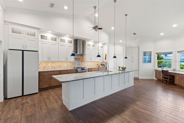 kitchen featuring wall chimney range hood, visible vents, crown molding, stainless steel gas range oven, and refrigerator