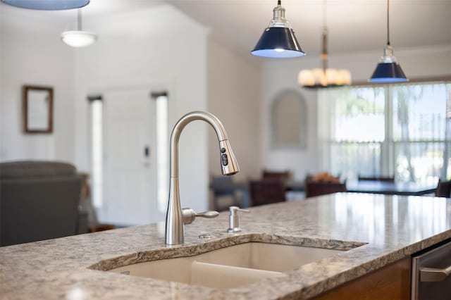 kitchen featuring hanging light fixtures, light stone counters, and a sink