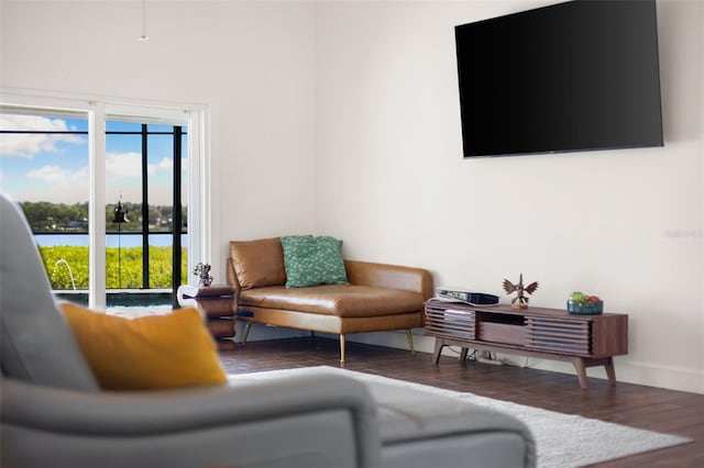 living area with a water view, baseboards, and wood finished floors