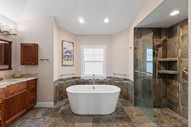 bathroom featuring a freestanding bath, vanity, a textured ceiling, and tiled shower