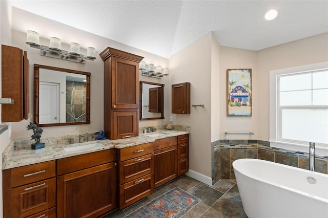 bathroom with a sink, double vanity, baseboards, lofted ceiling, and a soaking tub