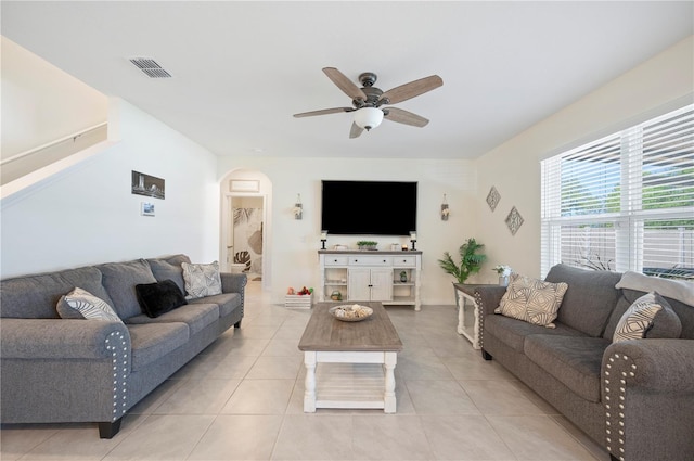 living room featuring arched walkways, a ceiling fan, light tile patterned flooring, and visible vents