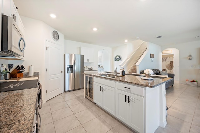 kitchen with arched walkways, appliances with stainless steel finishes, a sink, and wine cooler