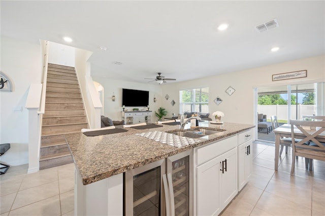 kitchen with light stone countertops, visible vents, a sink, and wine cooler