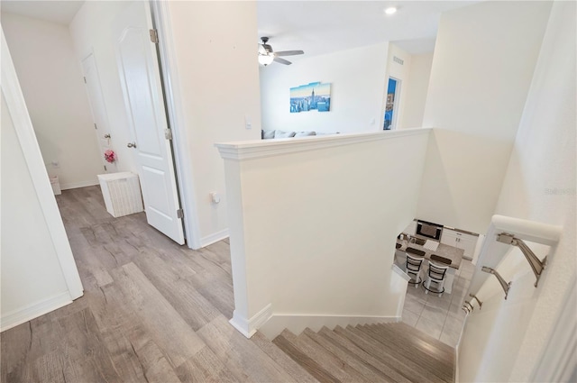 stairway with baseboards, ceiling fan, and wood finished floors