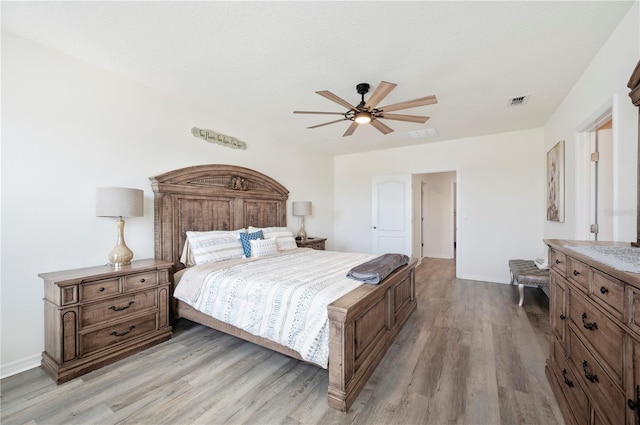 bedroom with baseboards, visible vents, ceiling fan, and light wood finished floors