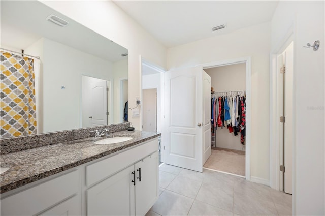bathroom featuring tile patterned floors, visible vents, a spacious closet, and vanity