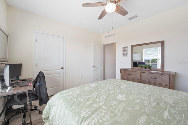 bedroom with a ceiling fan, wood finished floors, and visible vents