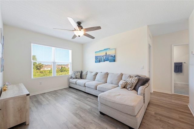 living area featuring baseboards, a ceiling fan, and wood finished floors