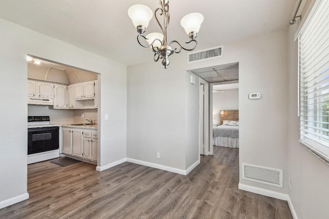unfurnished dining area featuring visible vents, wood finished floors, and a chandelier